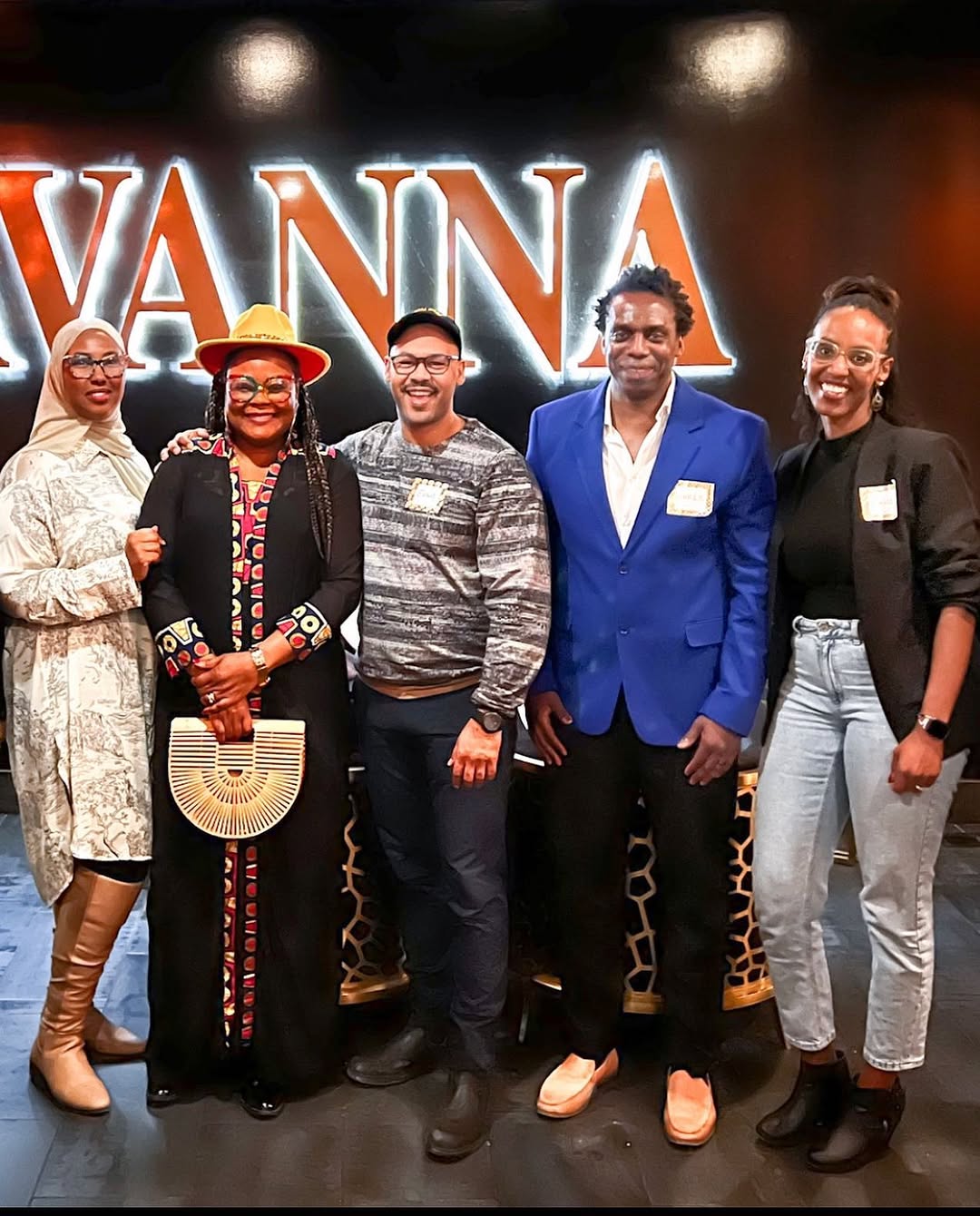 People standing together for a group photo in front of an illuminated sign at an event.