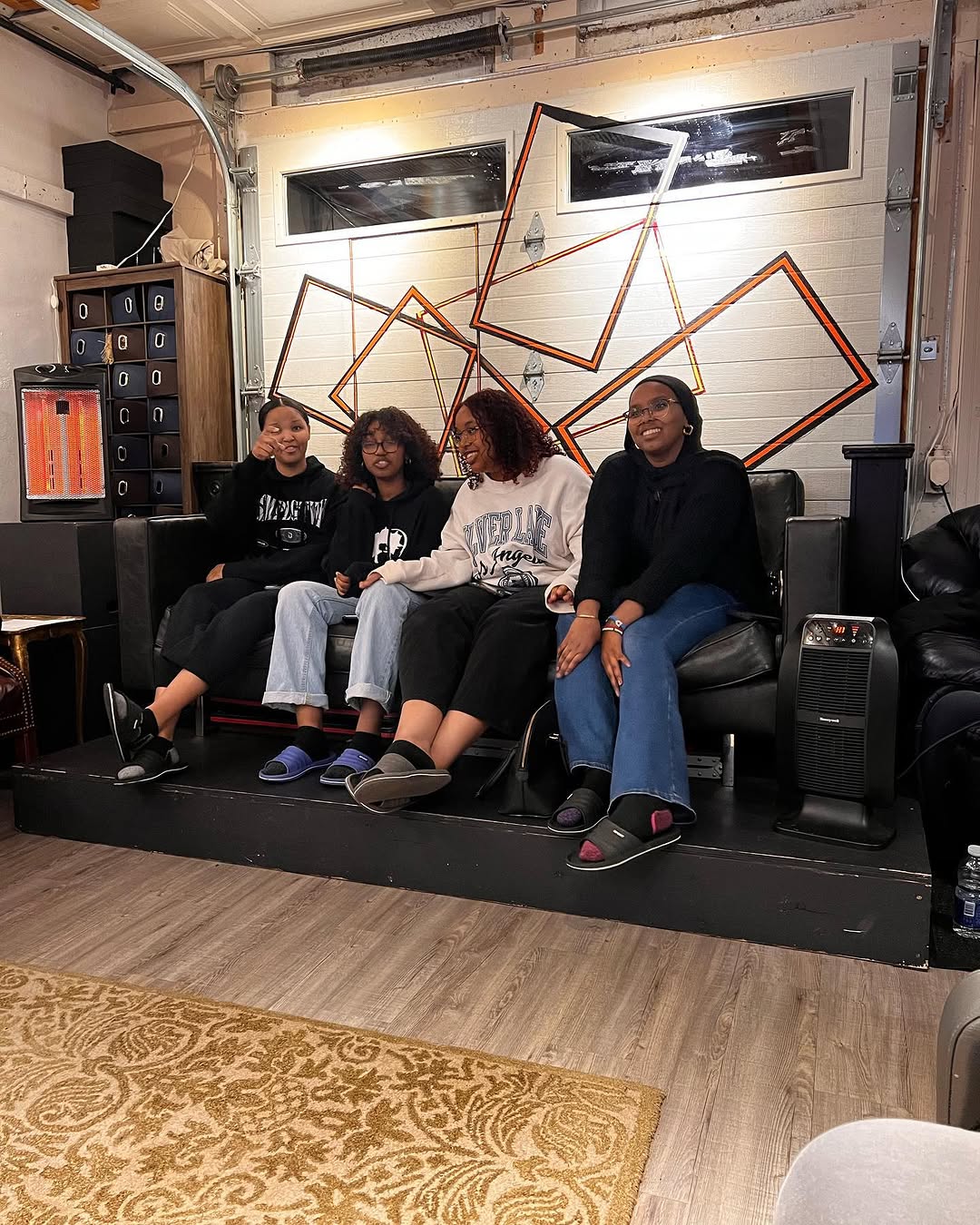 Four young people sitting together on a sofa in an indoor community space.