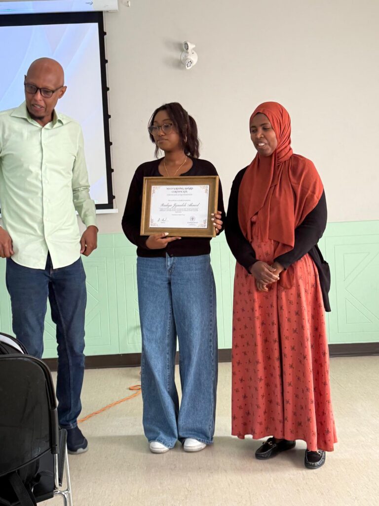 Two people holding a framed certificate at an indoor event.