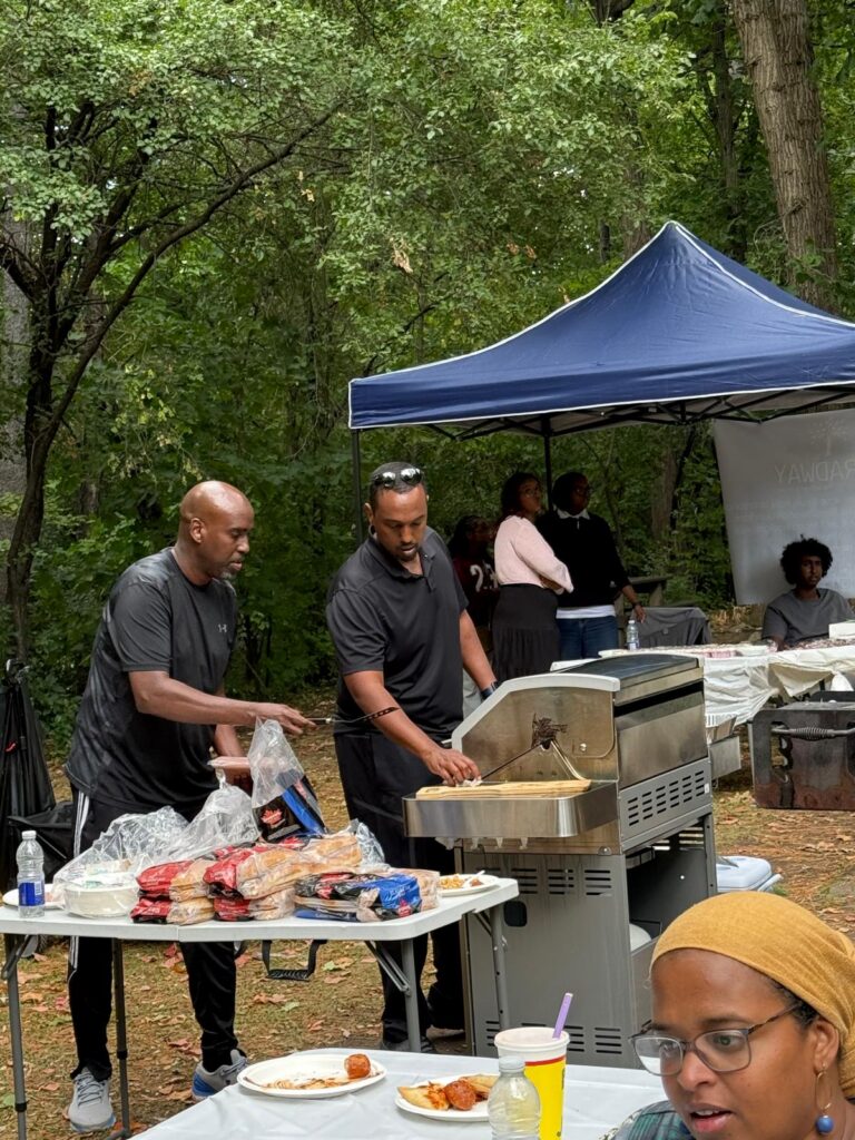 People preparing food at an outdoor barbecue.